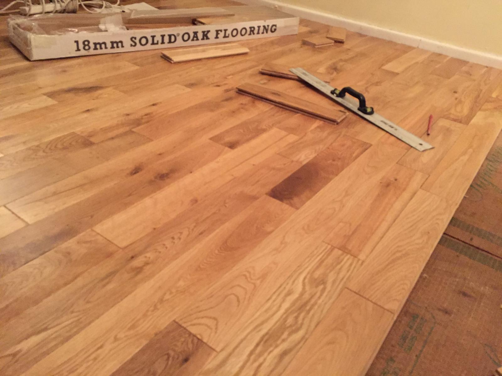 18mm solid oak flooring being laid, with a spirit level and offcuts on the boards