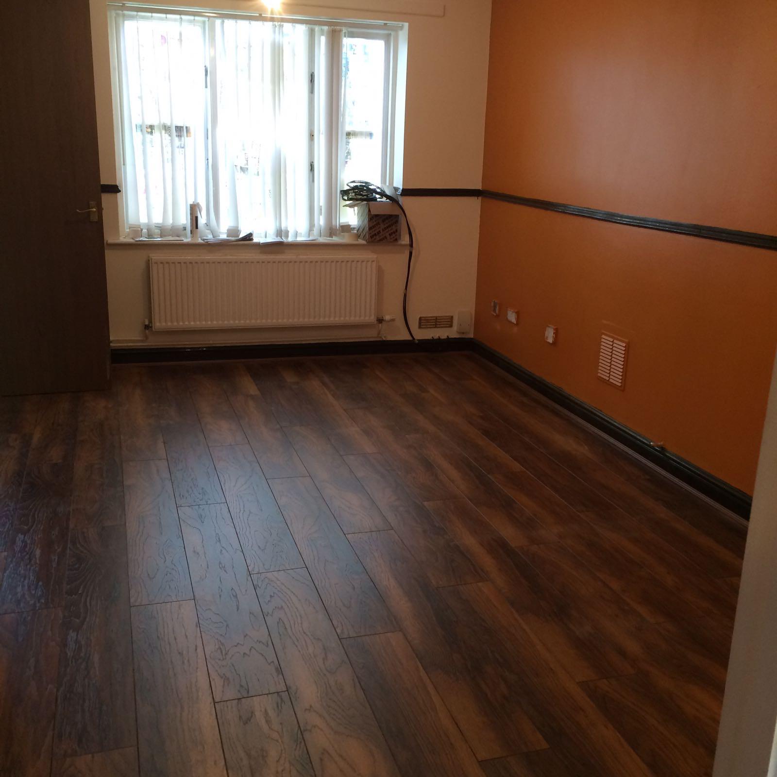 Living room finished with a burnt-orange feature wall and dark laminate flooring
